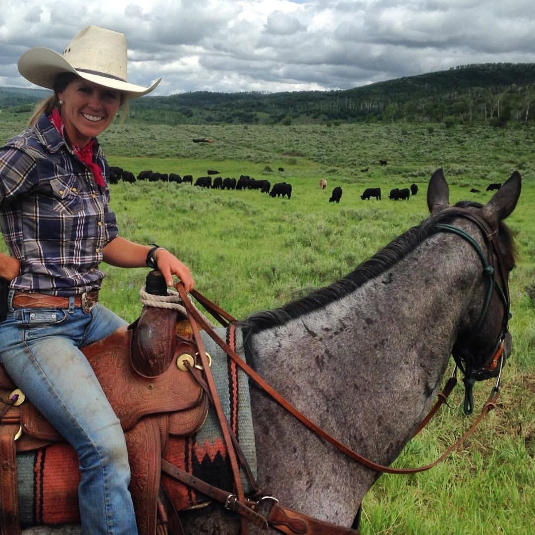 Mandy Griffey riding a gray horse on a Colorado ranch