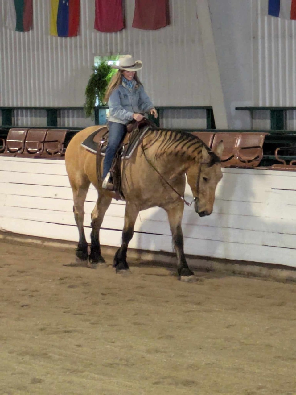 Mandy riding a dun horse during an arena training session
